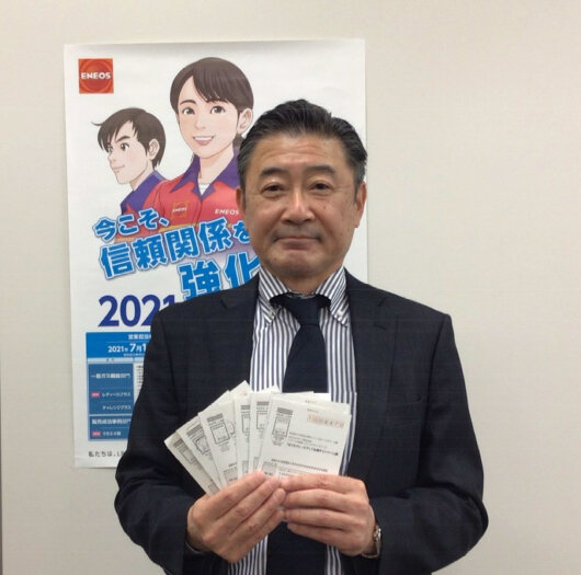 ５０,０００円分のＪＣＢギフトカード当選者の応募はがきを持つ結束部長